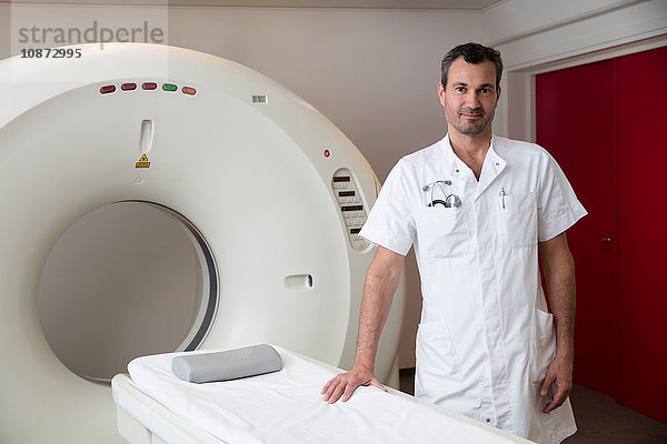 Porträt eines Arztes  der neben einem CT-Scanner steht