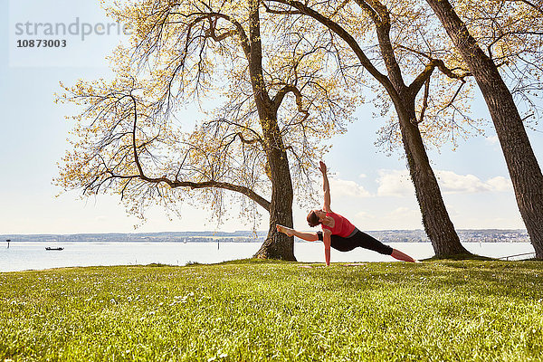 Frau mit angehobenem Arm und Bein in Yogastellung