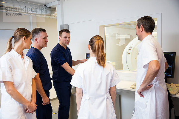 Ärzte und Krankenschwestern begutachten Röntgenbilder auf dem Monitor im CT-Kontrollraum