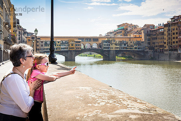 Ältere Frau und Enkelin zeigen auf den Fluss Arno  Florenz  Italien