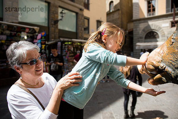 Ältere Frau und Enkelin mit der Hand unter einem Wasserbrunnen  Florenz  Italien