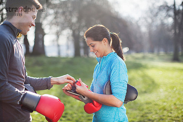 Junger Mann und Frau ziehen Boxhandschuhe zum Training im Park an