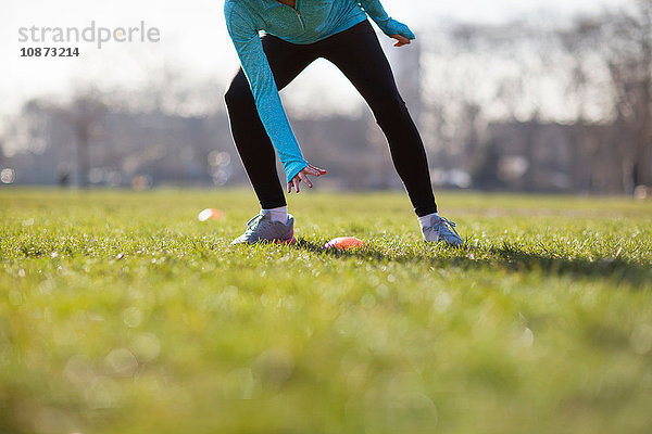 Taille nach unten Ansicht einer jungen Frau beim Training  Berühren eines Kegelmarkers auf dem Spielfeld