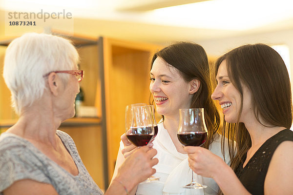 Frauen halten Gläser mit Rotwein und stoßen darauf an