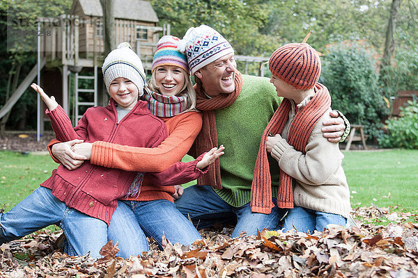 Porträt einer Familie  die im Herbstlaub sitzt