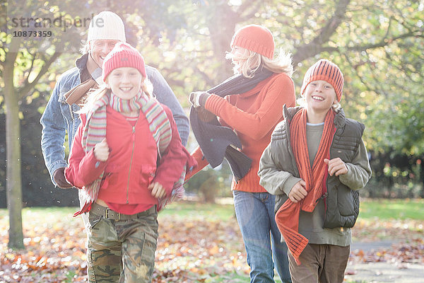 Familie amüsiert sich im Park  spaziert durch das Herbstlaub