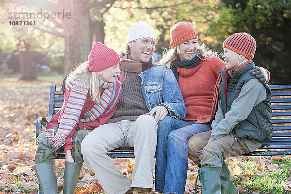 Familie sitzt zusammen auf der Parkbank und lacht