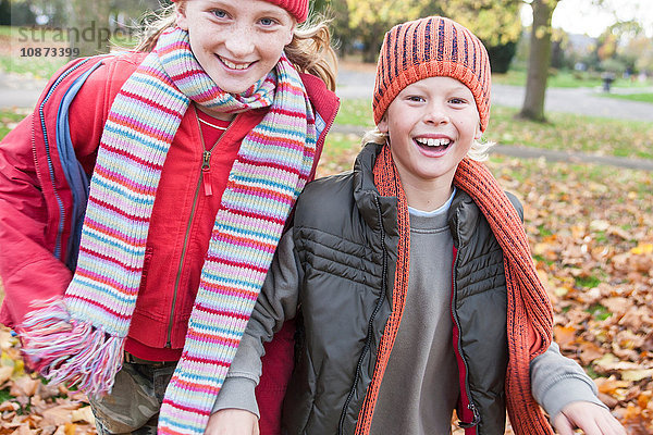 Bruder und Schwester gehen gemeinsam lächelnd durch den Park