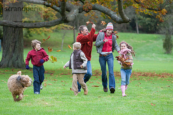 Familie albert im Park herum und wirft Herbstblätter