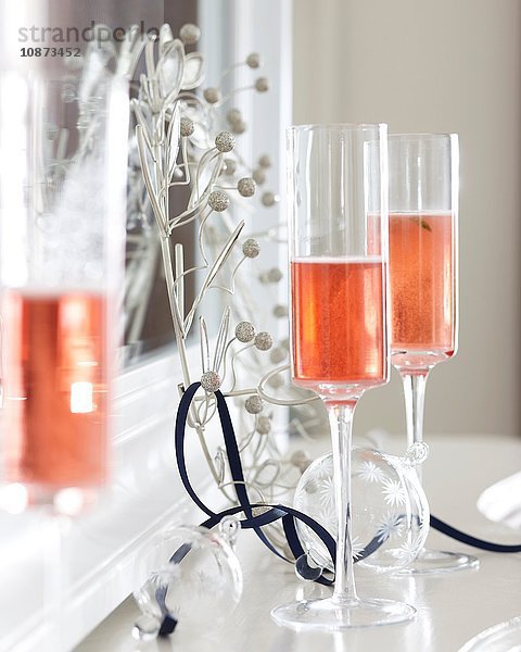 Champagnerflöten aus rosa Champagner auf Kaminsims mit Weihnachtsdekoration