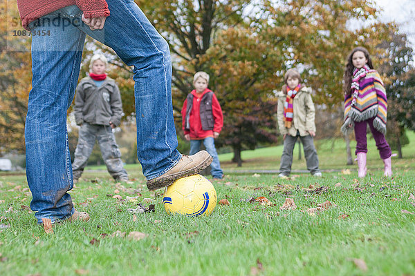 Vater und Kinder beim Fussballspielen im Park