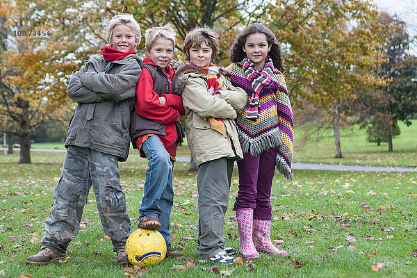 Porträt von vier Kindern mit Fussball im Park