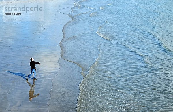 Hochwinkel-Seitenansicht eines reifen Mannes am Strand  der Steine ins Meer wirft