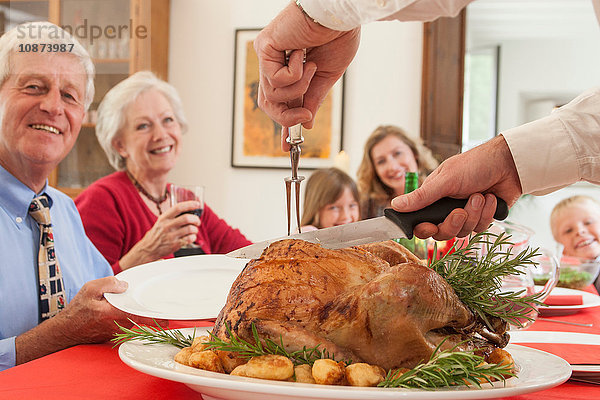 Mann schneidet Truthahn für Familie beim Weihnachtsessen auf