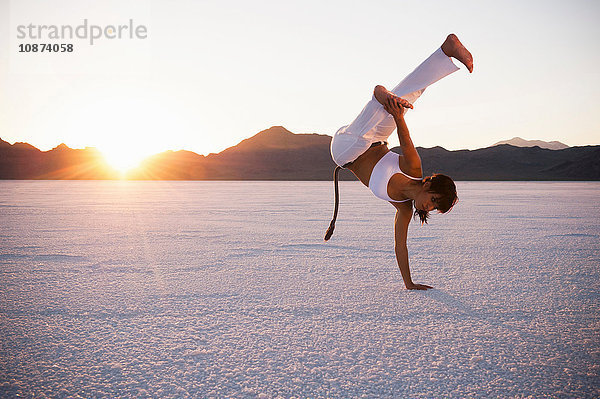 Frau spielt Capoeira auf den Bonneville Salt Flats bei Sonnenuntergang  Utah  USA