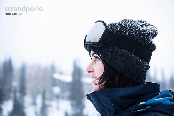 Porträt einer jungen Frau mit Skibrille  die in den Schnee starrt  Brighton Ski Resort ausserhalb von Salt Lake City  Utah  USA