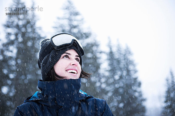 Porträt einer jungen Frau mit Skibrille  die zum Schnee hochschaut  Brighton Ski Resort ausserhalb von Salt Lake City  Utah  USA