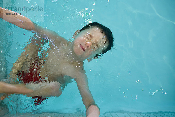 Junge mit geschlossenen Augen  mit Kopf über Wasser im Schwimmbecken