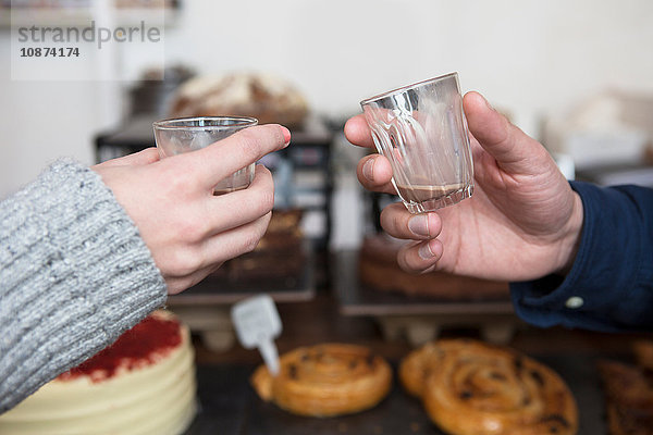 Nahaufnahme der Hände eines Paares  das im Café einen Espresso-Toast ausbringt