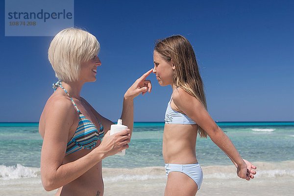 Junge Frau cremt die Nase von Töchtern am Strand mit Sonnencreme ein  Mallorca  Spanien