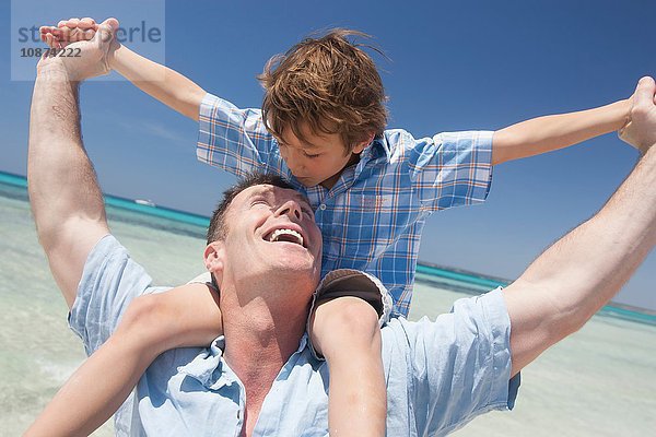 Junge wird am Strand vom Vater an der Schulter getragen  Mallorca  Spanien