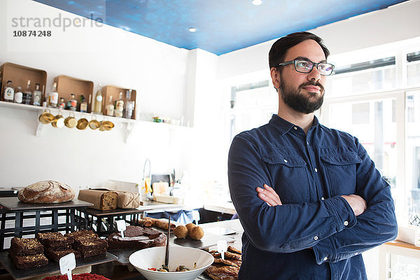 Porträt eines männlichen Café-Besitzers im mittleren Erwachsenenalter an der Küchentheke