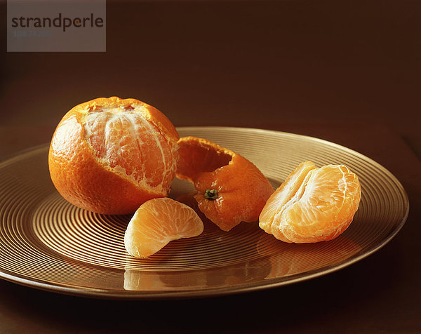 Essen  Früchte  Clementine halb geschält auf goldenem Teller