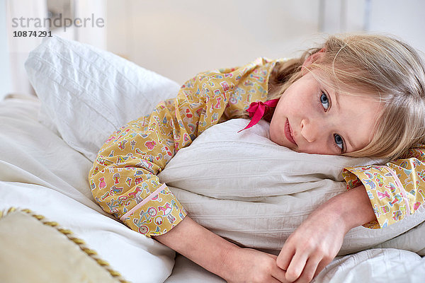 Mädchen im Schlafanzug tagträumend im Bett