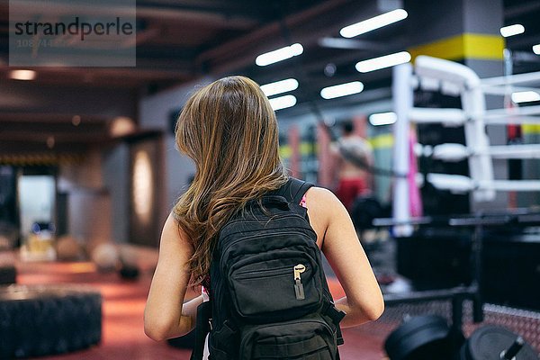 Rückansicht einer jungen Frau  die einen Rucksack trägt und sich auf das Fitnessstudio vorbereitet