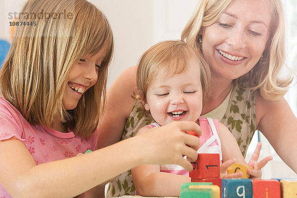Große Schwester hilft Baby-Mädchen  Bausteine lächelnd zu stapeln