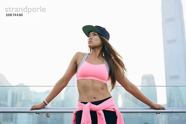 Porträt einer jungen Frau mit rosa Oberteil und Baseballmütze am Hafen  Hongkong