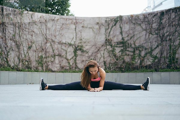 Junge Frau beim Sport im Freien beim Spagat