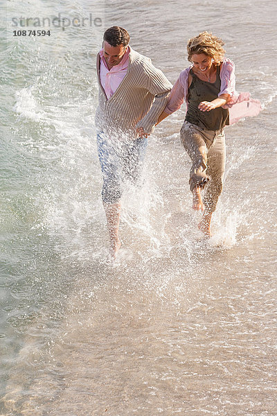 Glückliches reifes Paar rennt und planscht im Meer  Mallorca  Spanien