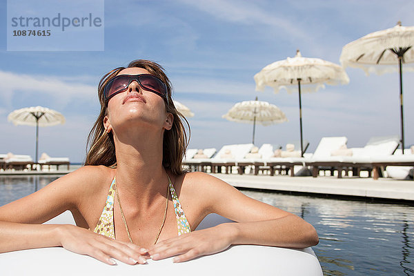 Coole junge Frau mit Sonnenbrille am Pool lehnt am Strand eines Strandresorts  Mallorca  Spanien
