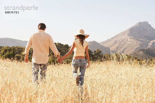 Rückansicht eines Paares beim Spaziergang auf einem Feld aus Langgras  Mallorca  Spanien