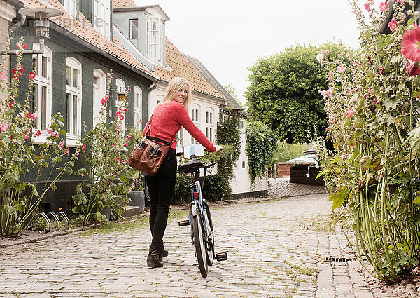 Frau schiebt Fahrrad auf Kopfsteinpflasterstraße  Aarhus  Dänemark