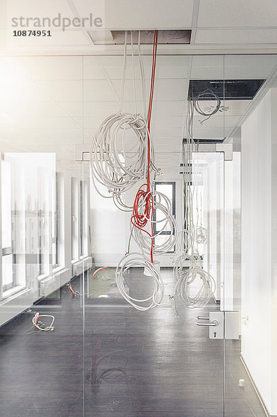 Netzwerk- und Stromkabel hängen von der Decke des neuen Bürokorridors