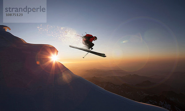 Skifahrer springt bei Sonnenuntergang auf einem verschneiten Hang  Zermatt  Kanton Wallis  Schweiz