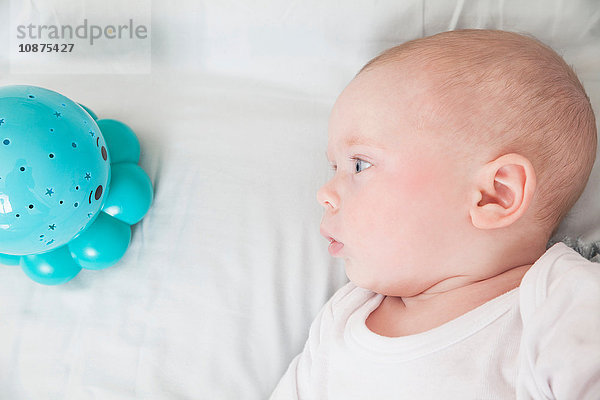 Kleiner Junge starrt auf blaues Babyspielzeug  Draufsicht