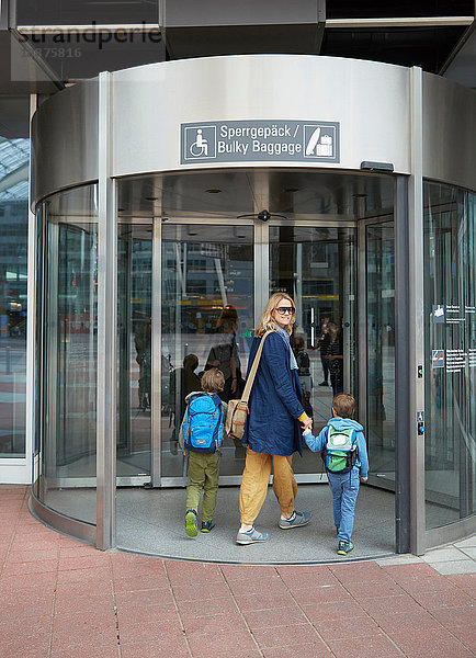 Rückansicht von Mutter und Söhnen beim Betreten des Flughafenterminals