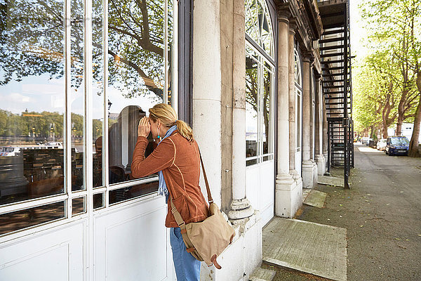 Frau  die die Augen beim Blick durchs Fenster abschirmt