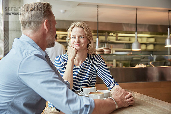 Reifes Paar im Café  das sich an den Händen hält und plaudert