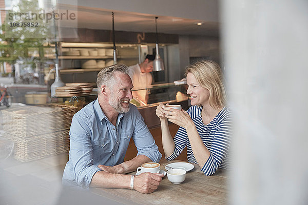 Blick durch das Fenster eines reifen Paares beim Kaffeehausgespräch