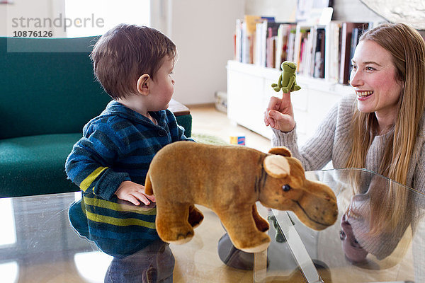 Mittlere erwachsene Frau und kleiner Sohn spielen mit Fingerpuppe im Wohnzimmer