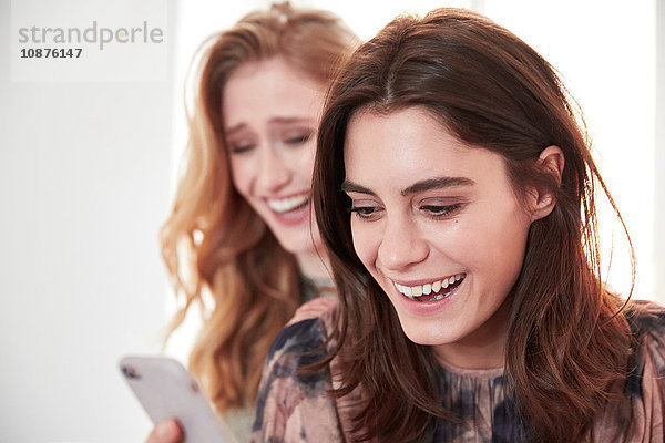 Zwei junge Frauen lachen über Smartphone-Texte