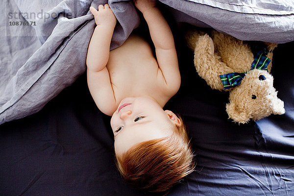 Draufsicht eines im Bett liegenden Mädchens und Teddybären