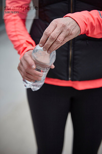 Schnappschuss einer reifen Frau beim Training  Öffnen einer Wasserflasche