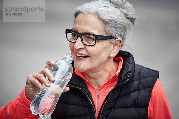 Ausbildung einer reifen Frau in der Stadt  Trinken von Flaschenwasser