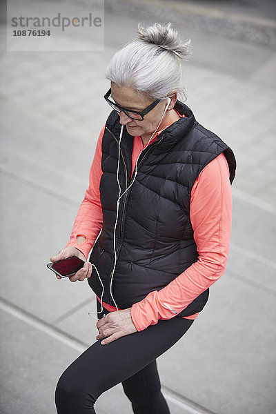 Reife Frau trainiert in der Stadt  wählt Smartphone-Musik