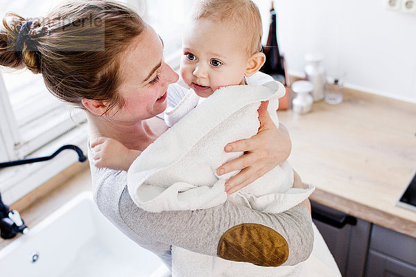 Mutter trägt Baby Sohn in Handtuch gewickelt